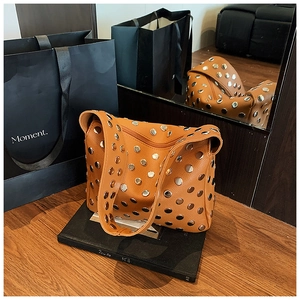 Detail of caramel leather shoulder bag with decorative silver rivets and natural texture