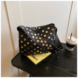 Detail of black pebbled leather shoulder bag featuring punk style silver metal rivets