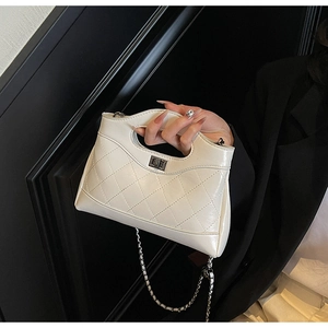 Detail of white quilted leather texture and silver twist lock on an elegant chain handbag