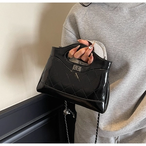 Detail of black quilted patent leather bag with silver twist lock and chain strap