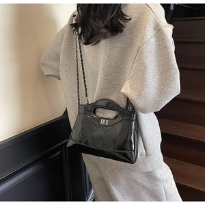 Detail showing glossy black quilted leather texture and metallic chain strap of shoulder bag