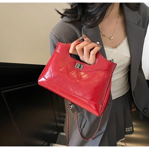 Detailed view of red quilted leather handbag with vintage metal lock and chain strap