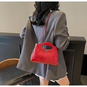 Detail of red quilted leather handbag with silver twist lock and chain strap on grey suit