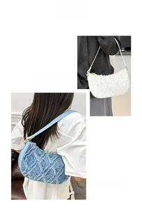 Detail of quilted denim crescent bag with frayed edges and golden hardware in blue and white