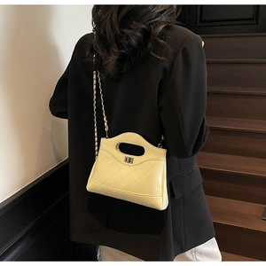 Quilted yellow chain bag worn by model in elegant black blazer over vintage stairs