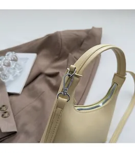 Detail der cremefarbenen Croissant-Tasche aus Leder mit hochwertigen Silberbeschlägen