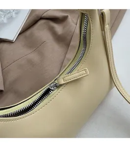 Detailansicht des glatten Silberreißverschlusses und der cremefarbenen Ledertextur der Tasche
