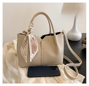 Detail of off-white lychee leather tote with silk scarf and smartphone for scale