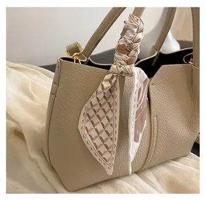 Detail of geometric print silk scarf wrapped around a beige leather tote handle