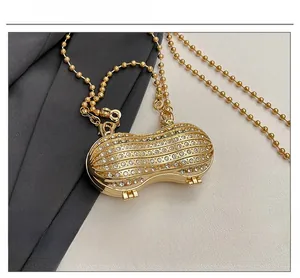 Detailed close-up of a peanut-shaped gold pendant necklace with inlaid white crystals