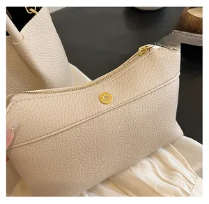 Detail of beige lychee textured leather bag with gold zipper and magnetic snap closure
