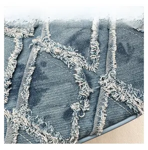 Detail display of blue denim fabric with fringe quilting and diamond lattice texture