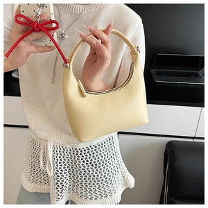 Detail einer cremegelben Halbmond-Handtasche von einem Model in modernem Interieur