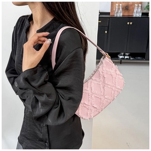Close-up of pink quilted canvas handbag with fringe texture and metal zipper detail