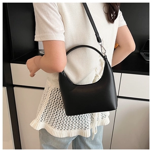 Detail einer schwarzen Halbmond-Tasche mit rundem Griff und schmalem Schultergurt