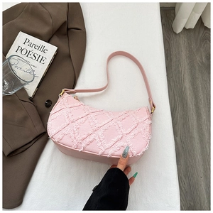 Detail of pink crescent bag with textured frayed diamond pattern and golden hardware