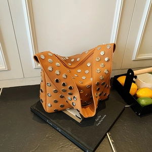Fashionable ginger leather shoulder bag featuring large silver rivets and wide strap