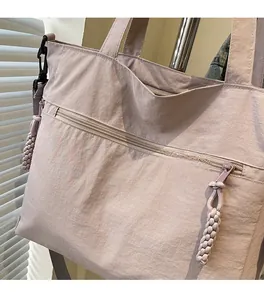 Detail of pink nylon tote bag with unique woven rope zipper and metal strap hooks
