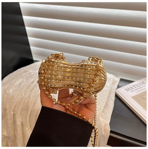 Detail of peanut-shaped evening bag with gold metallic texture and sparkling rhinestones
