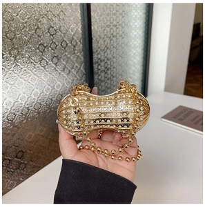 Detailed view of a peanut-shaped golden evening bag with sparkling rhinestones and bead chain