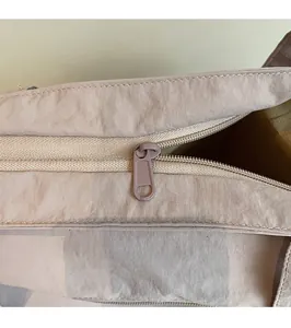 Detail of a smooth zipper closure on a canvas tote bag with a matte finish puller