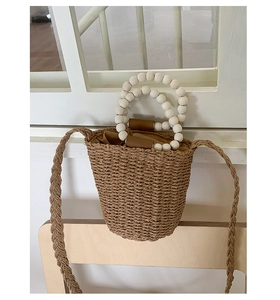 Close-up of woven straw bucket bag featuring white beaded handles and textured surface