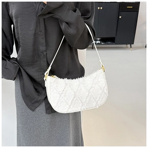 Detail of white quilted texture and fringe finish on a modern crescent shoulder bag