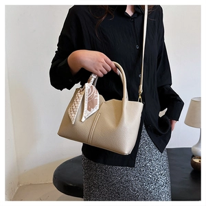 Detail of beige tote bag featuring textured leather, double handles and stylish silk scarf