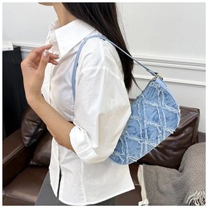 Close-up of quilted denim shoulder bag with white fringe trim worn by a model