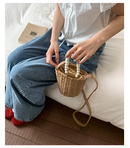 Detail of hand-woven straw bucket bag with pearl handle and drawstring inner pouch