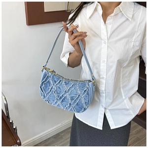 Detail of light blue denim underarm bag with quilted texture and gold metal zipper