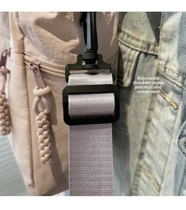 Detail of adjustable woven shoulder strap with black plastic buckle on beige tote bag