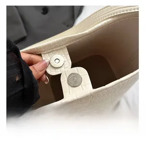 Detail of magnetic buckle and cream crocodile texture on high capacity bucket bag