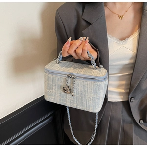 Detail of light blue tweed box bag with silver flower charm and woven chain strap