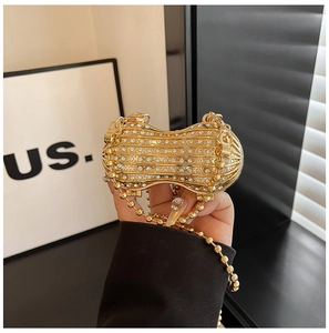 Detailed view of a peanut-shaped gold evening bag with sparkling rhinestones and chain