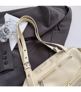 Détail de la bandoulière réglable et des ferrures argentées sur le sac en cuir crème