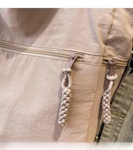Detailed close-up of beige nylon tote bag showing durable zipper with braided rope puller