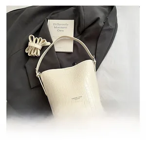 Detailed close-up of cream crocodile pattern bucket bag with elegant gold logo lettering