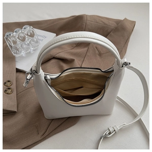 Detail der weißen Hobo-Tasche mit braunem Futter und Gurt auf einem braunen Blazer