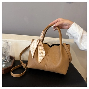 Detail of tan pebble leather tote bag with V-cut edge and decorative silk scarf