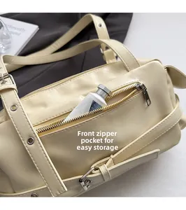 Détail de la poche zippée avant sur sac à main crème avec rivets et rangement pratique