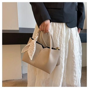 Detail of beige pebbled leather tote with a stylish checkered scarf wrap on handle