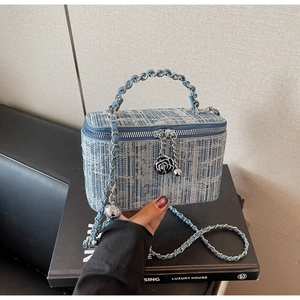 Detail of blue tweed box bag with silver chain strap and camellia charm zipper