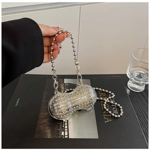 Macro shot of silver peanut-shaped evening bag with sparkly rhinestones and pearl chain