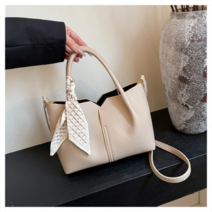 Detail of beige lychee texture leather tote with decorative silk scarf and thin strap