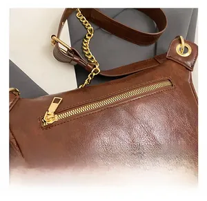 Detail of brown vintage leather chest bag with premium gold zipper and metal chain strap