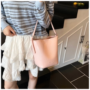 Close-up of pink crocodile pattern leather bucket bag with silver metal buckles