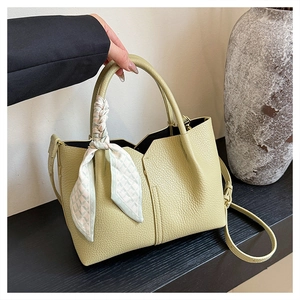 Detail of green litchi grain leather tote bag with elegant silk scarf on handle