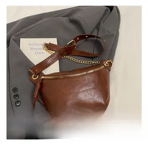 Detail view of brown vintage crescent chest bag with gold chain and leather fringe
