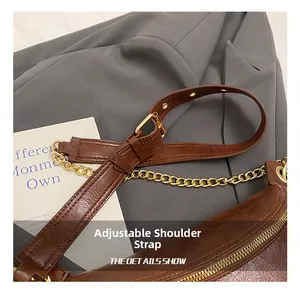 Detail of adjustable leather strap with gold chain links on a vintage brown chest bag